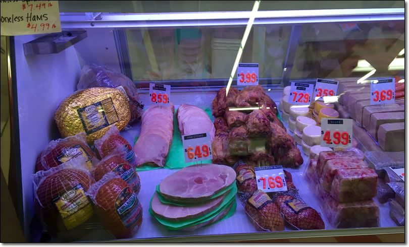 A display case filled with a variety of meats including hams