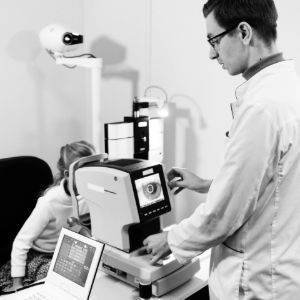 Two doctors examining a patient with a medical imaging machine and laptop in a clinic
