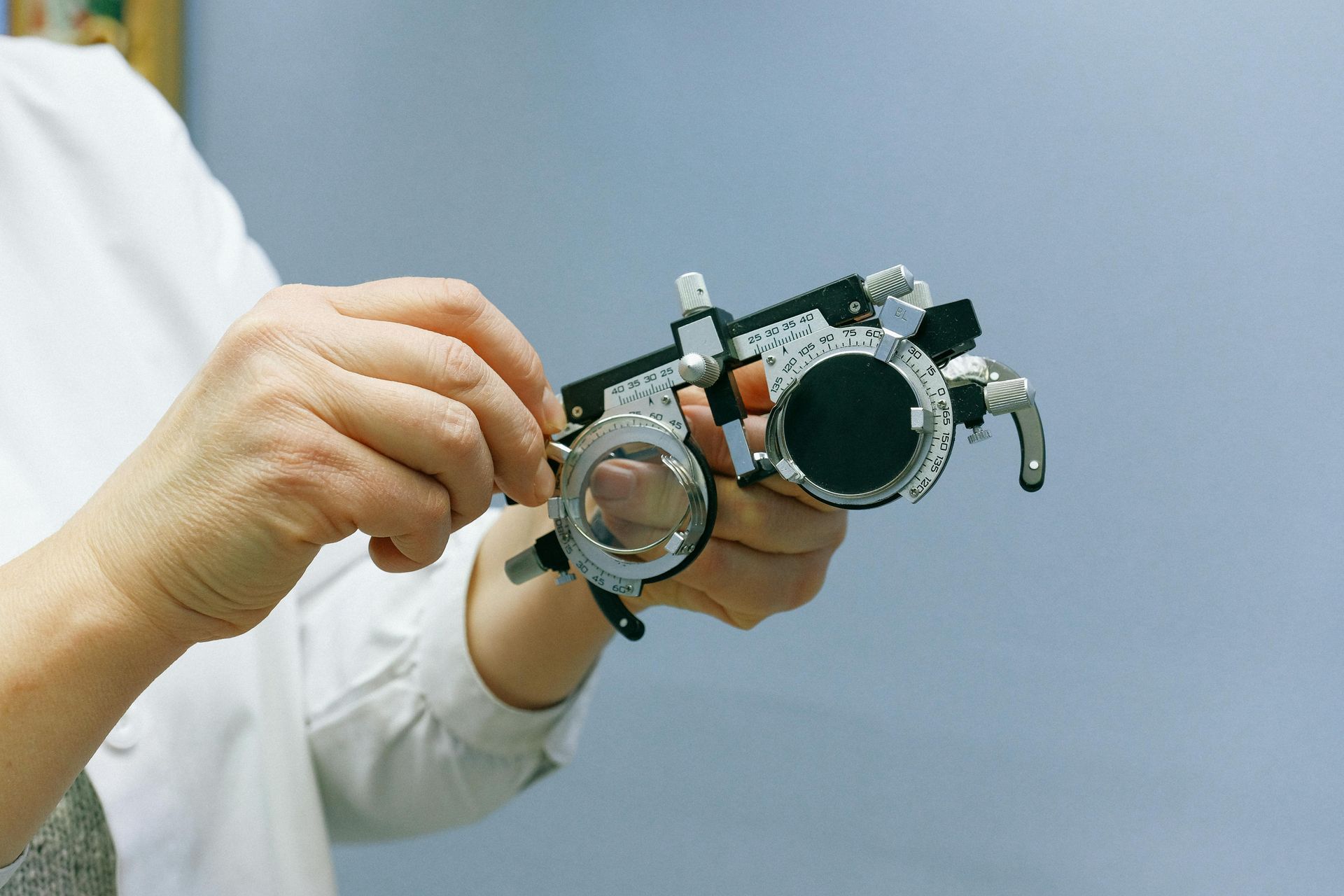 Hands holding optometry trial frames with lenses in a clinical setting