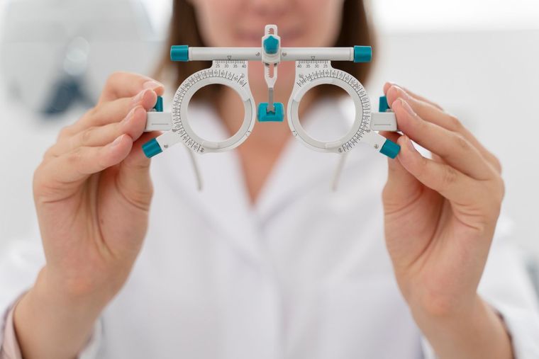 Three eyeglass frames on a wooden surface, with a black case behind them.