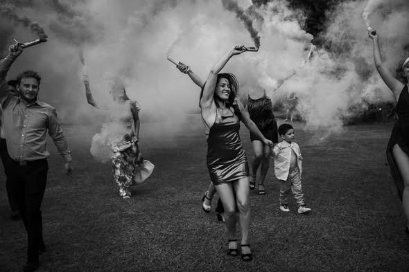 Personas caminando entre el humo con los brazos en alto sobre un campo de hierba