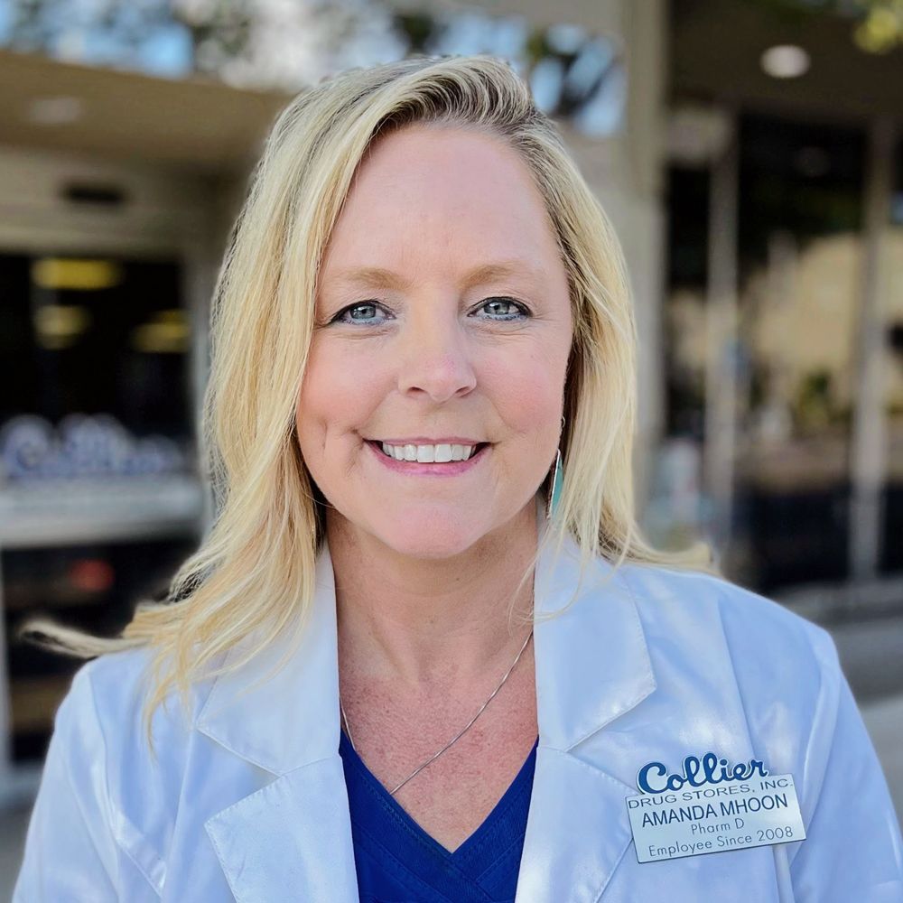 A woman in a lab coat and blue scrub is smiling for the camera.