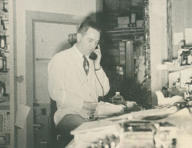 A man in a lab coat is talking on a phone