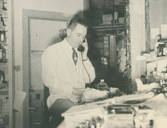 A man in a lab coat is talking on a phone