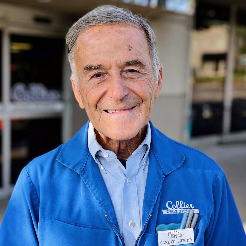 An older man wearing a blue jacket is smiling for the camera.