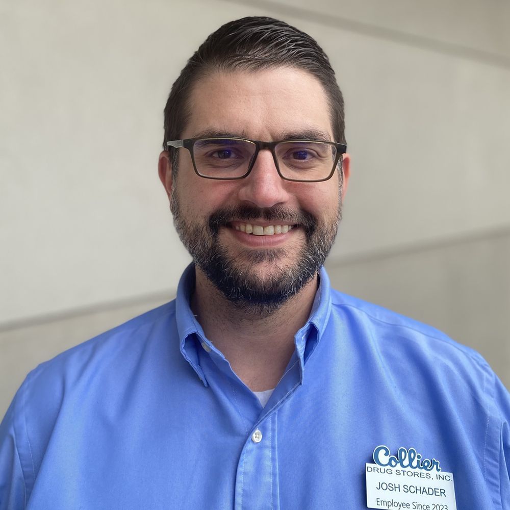 A man wearing glasses and a blue shirt is smiling for the camera.