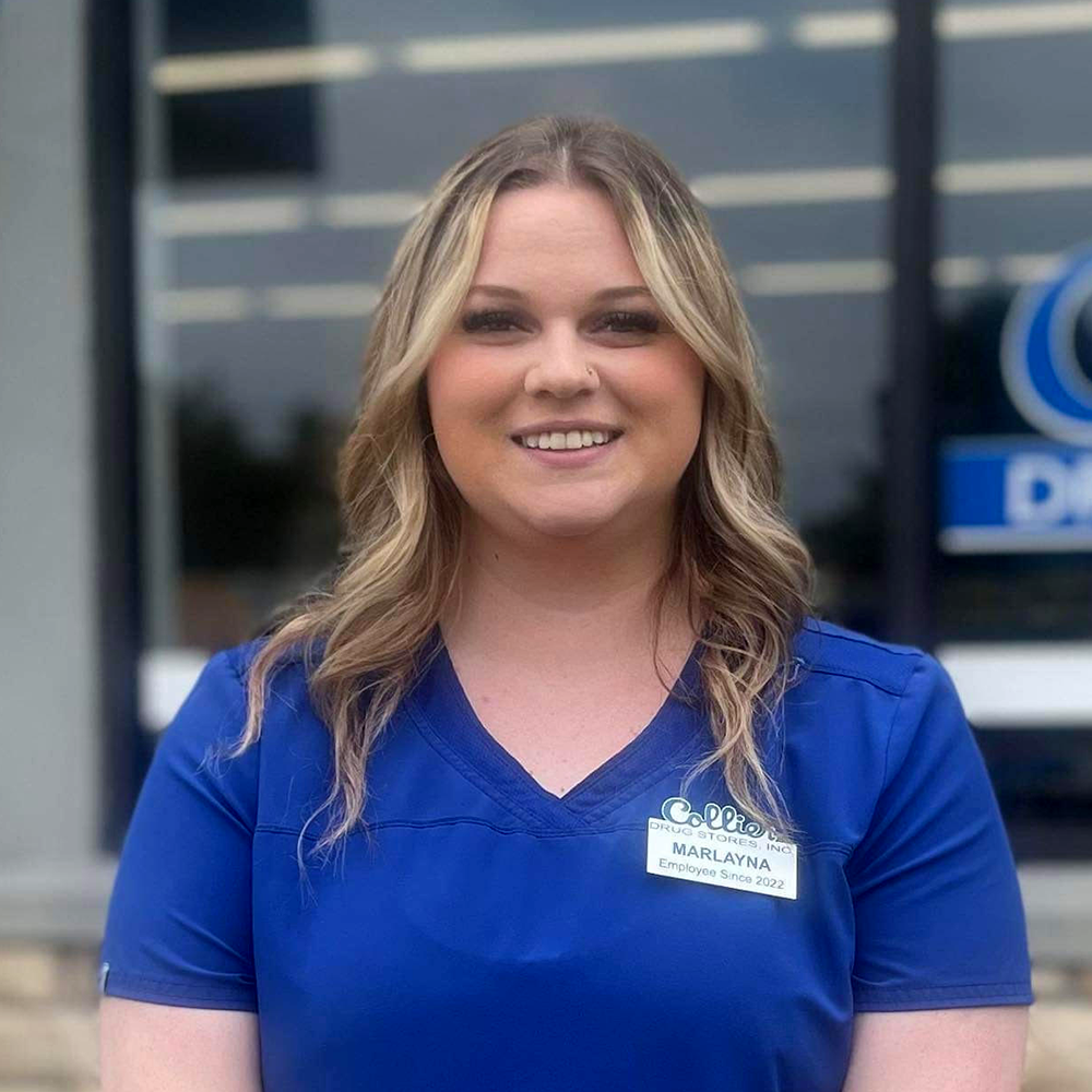A woman in a blue scrub top is smiling for the camera.