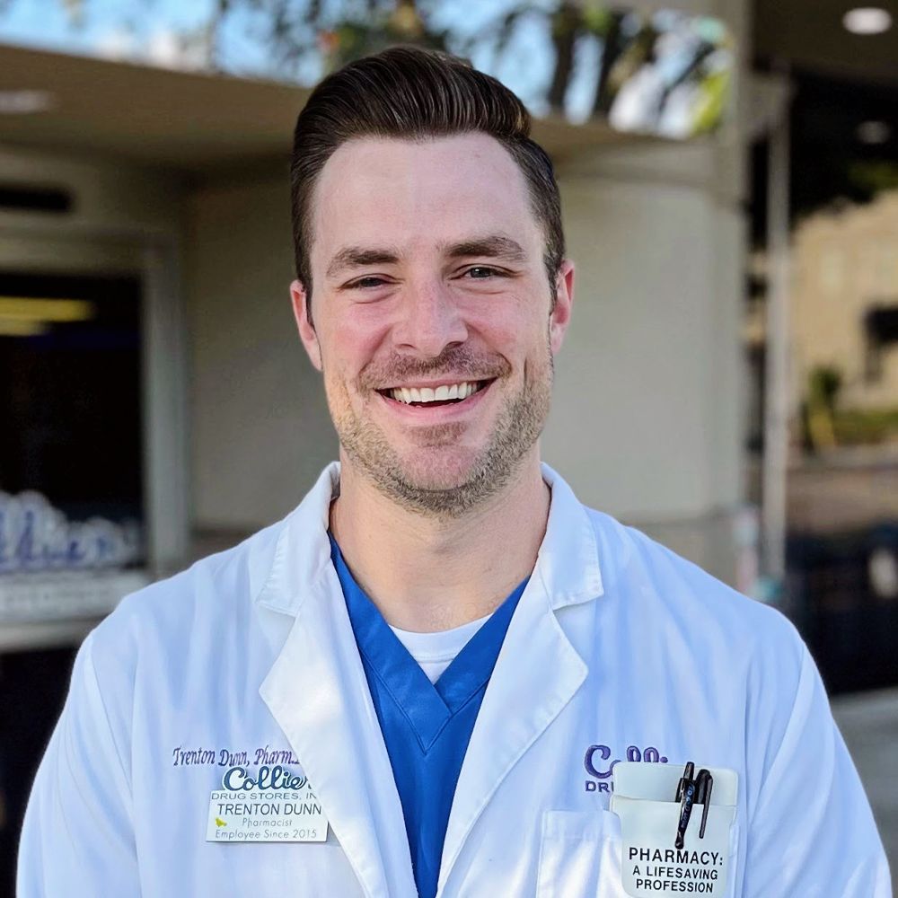 A man with a beard is wearing a white lab coat and blue scrubs.