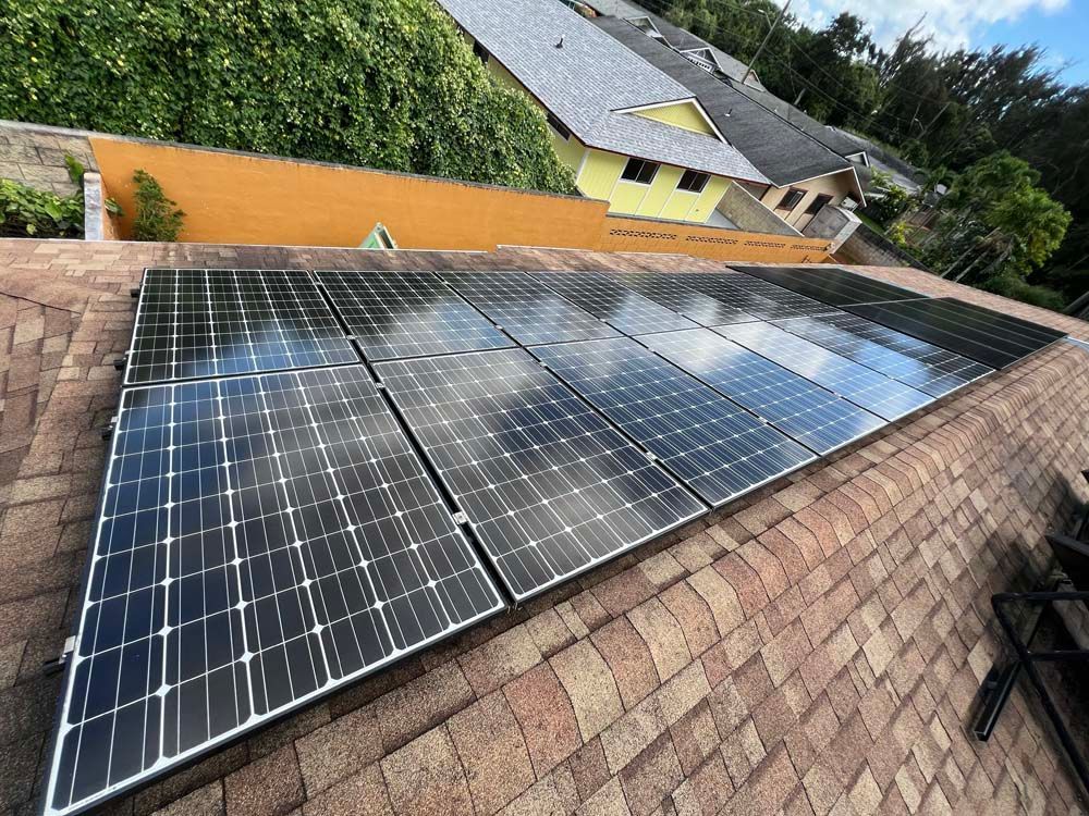 There are many solar panels on the roof of a house.