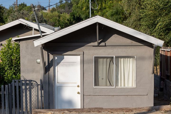 Small detached structure, ideal for garage conversion, with stucco and a door, by Albuquerque ADU Experts.