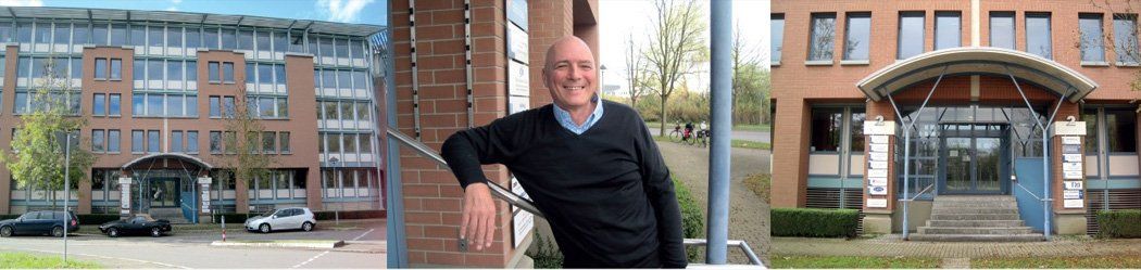 A man in a black sweater is standing in front of a building.