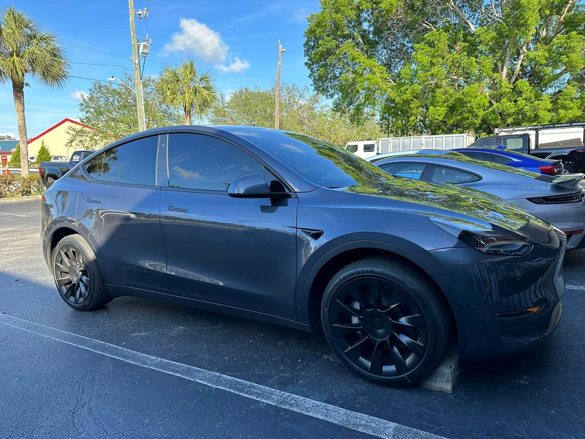 Gray Tesla SUV with dark side windows, viewed from the front and side.