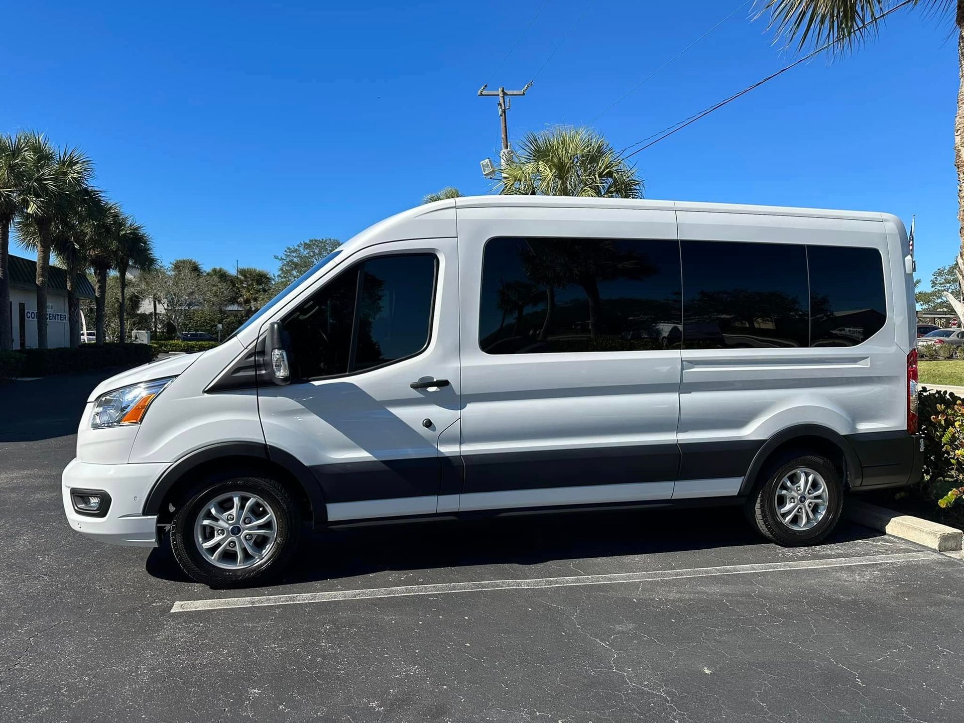 Silver Ford passenger van with dark side windows, shown in profile.