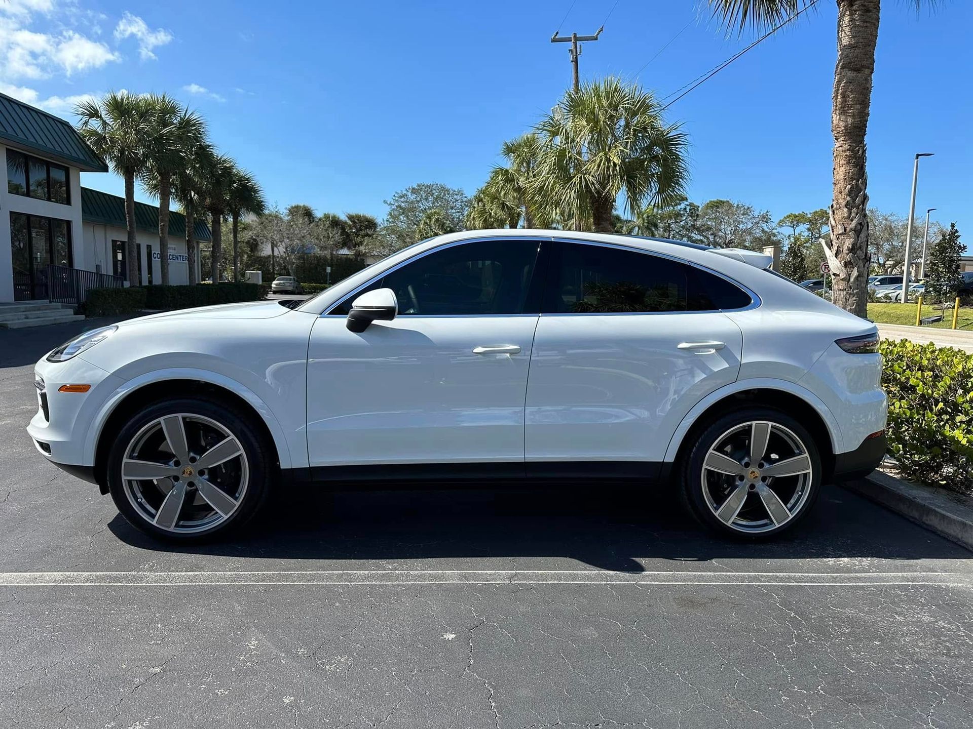 White Porsche SUV with dark side windows, shown in profile.