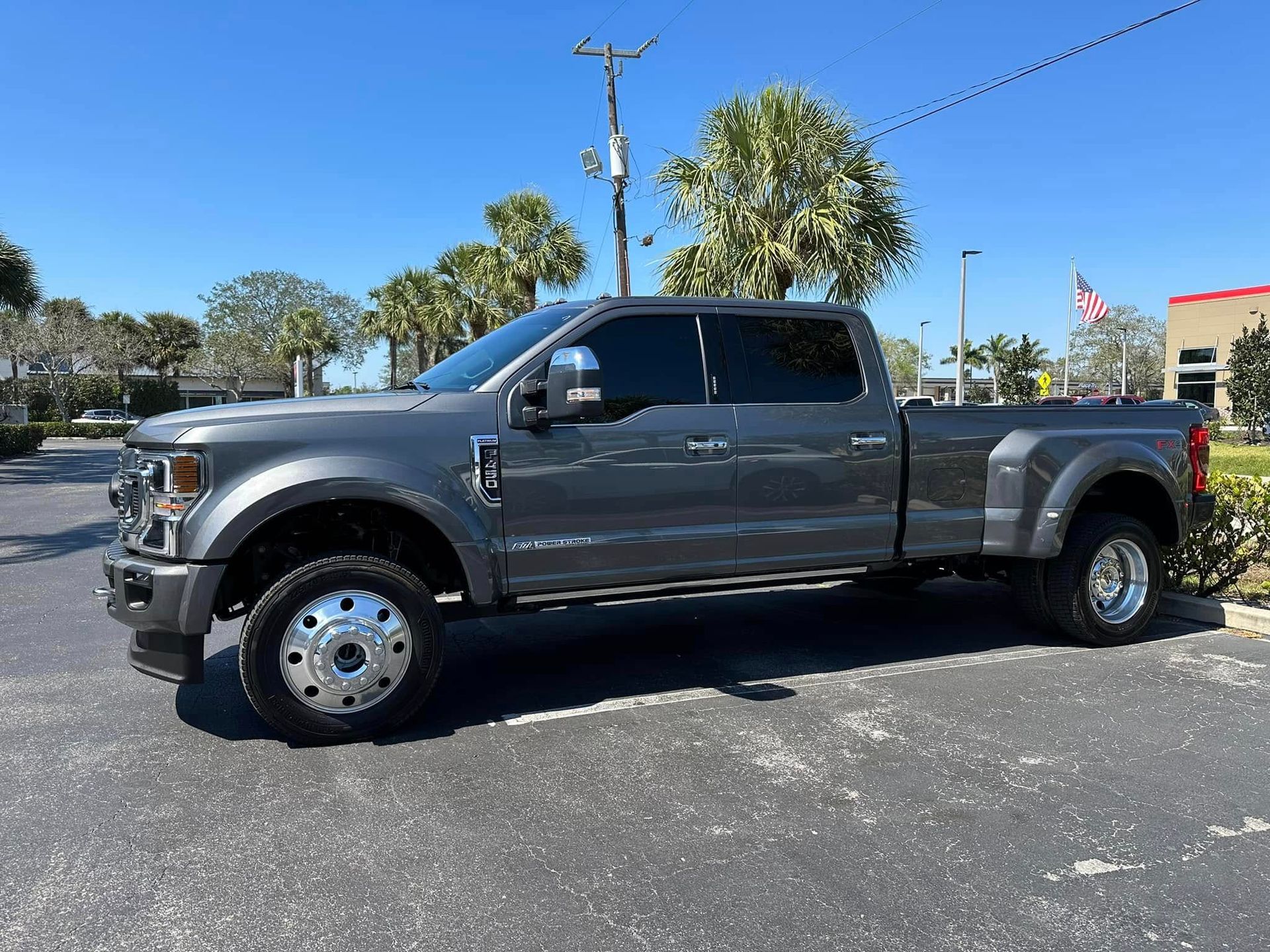 Gray Ford crew-cab pickup with dual rear wheels and dark side windows, shown in profile.