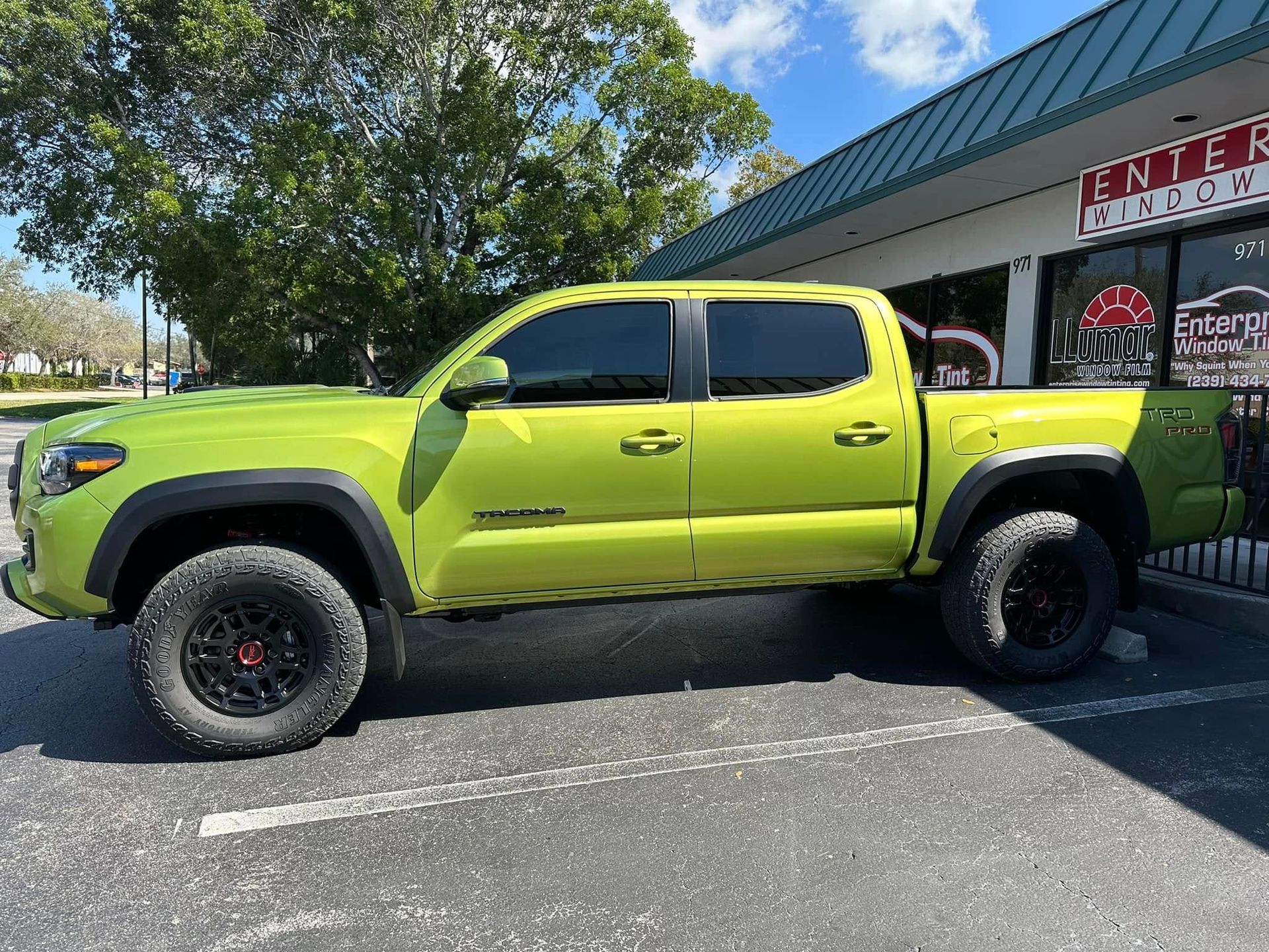 Lime-green Toyota pickup with dark side windows, shown in profile outside the tint shop.