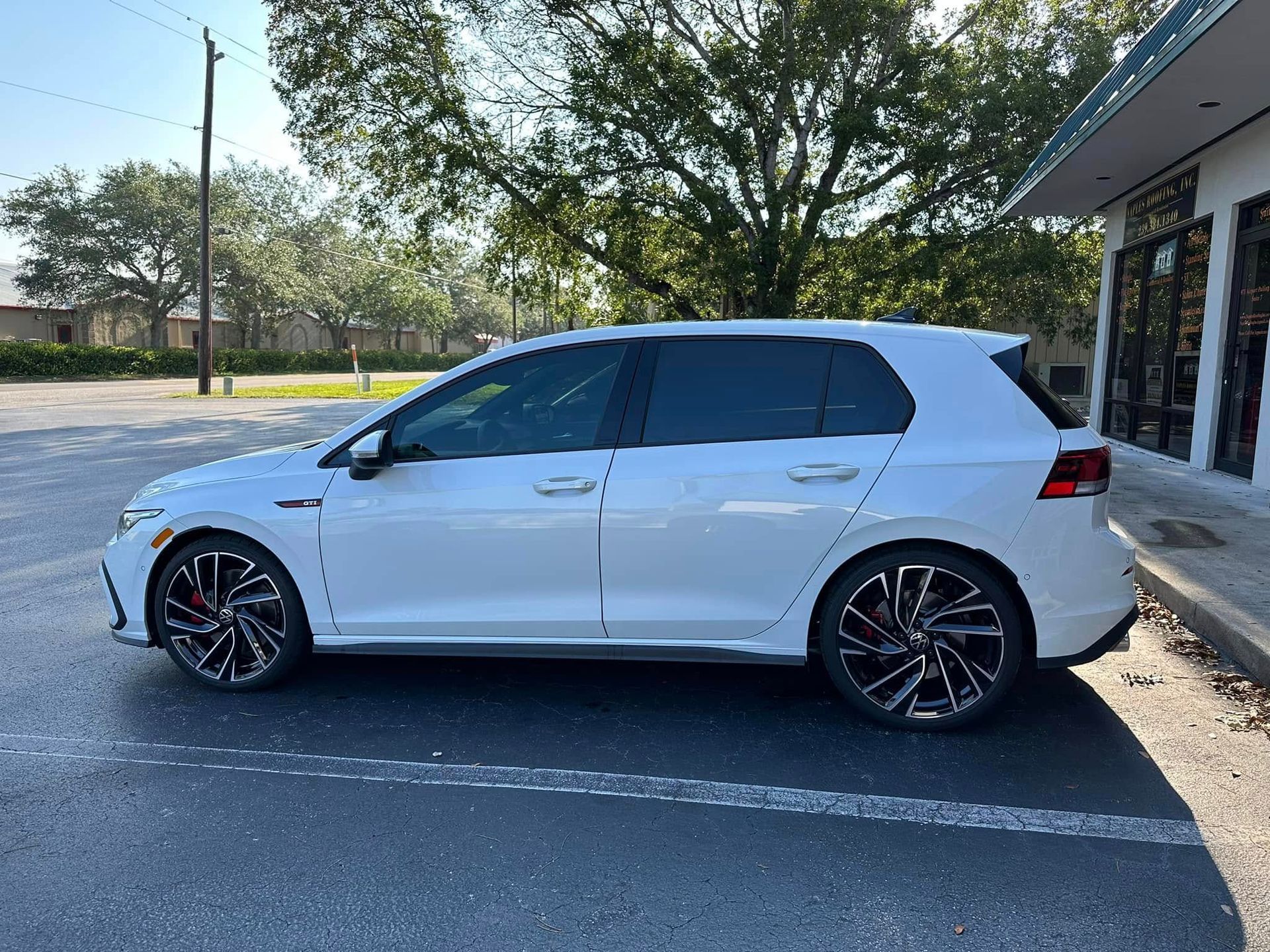 White Volkswagen hatchback with dark side windows and red brake calipers, shown in profile.