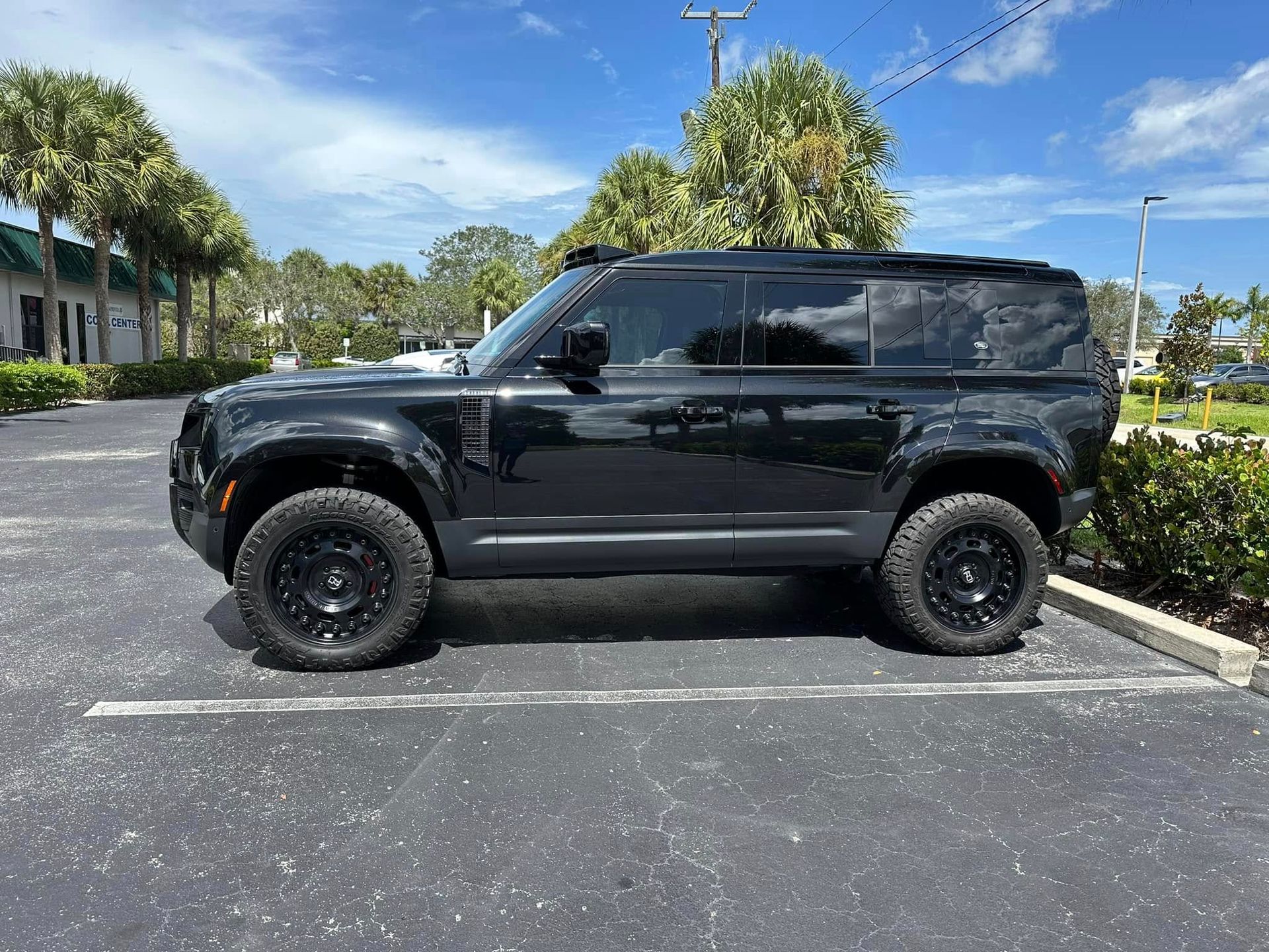 Black Land Rover SUV with dark side windows and off-road tires, shown in profile.