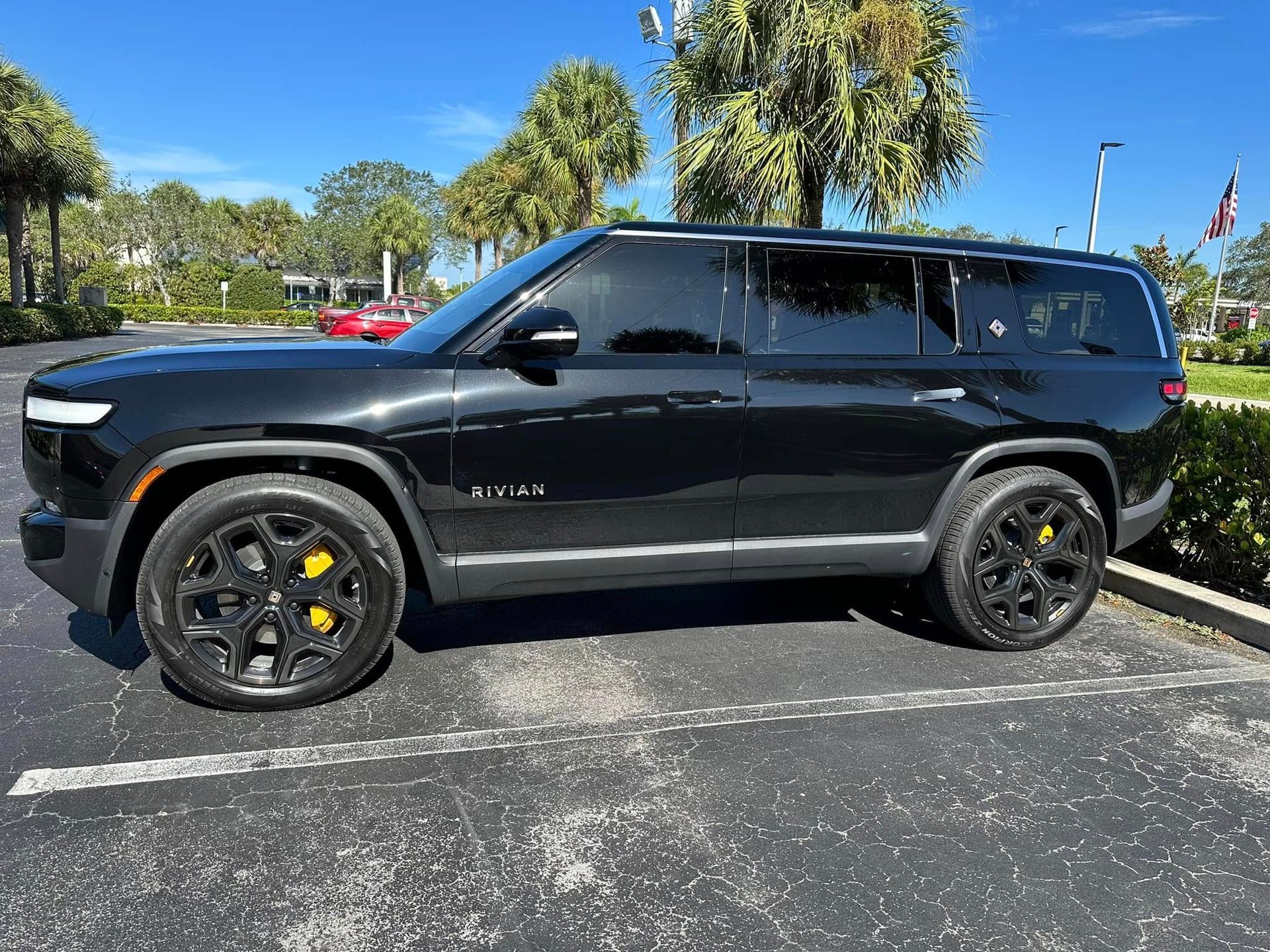 Black Rivian SUV with dark rear windows and yellow brake calipers, shown in profile.