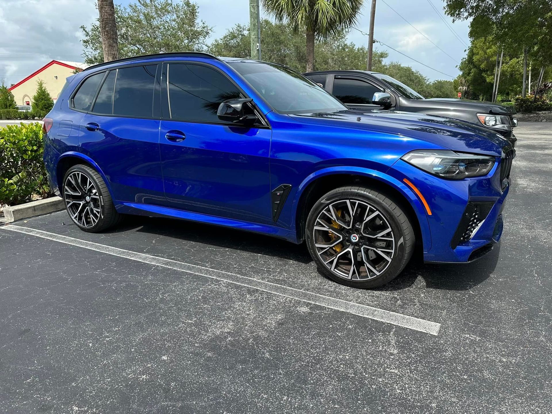 Blue BMW SUV with dark side windows, viewed from the front and side.