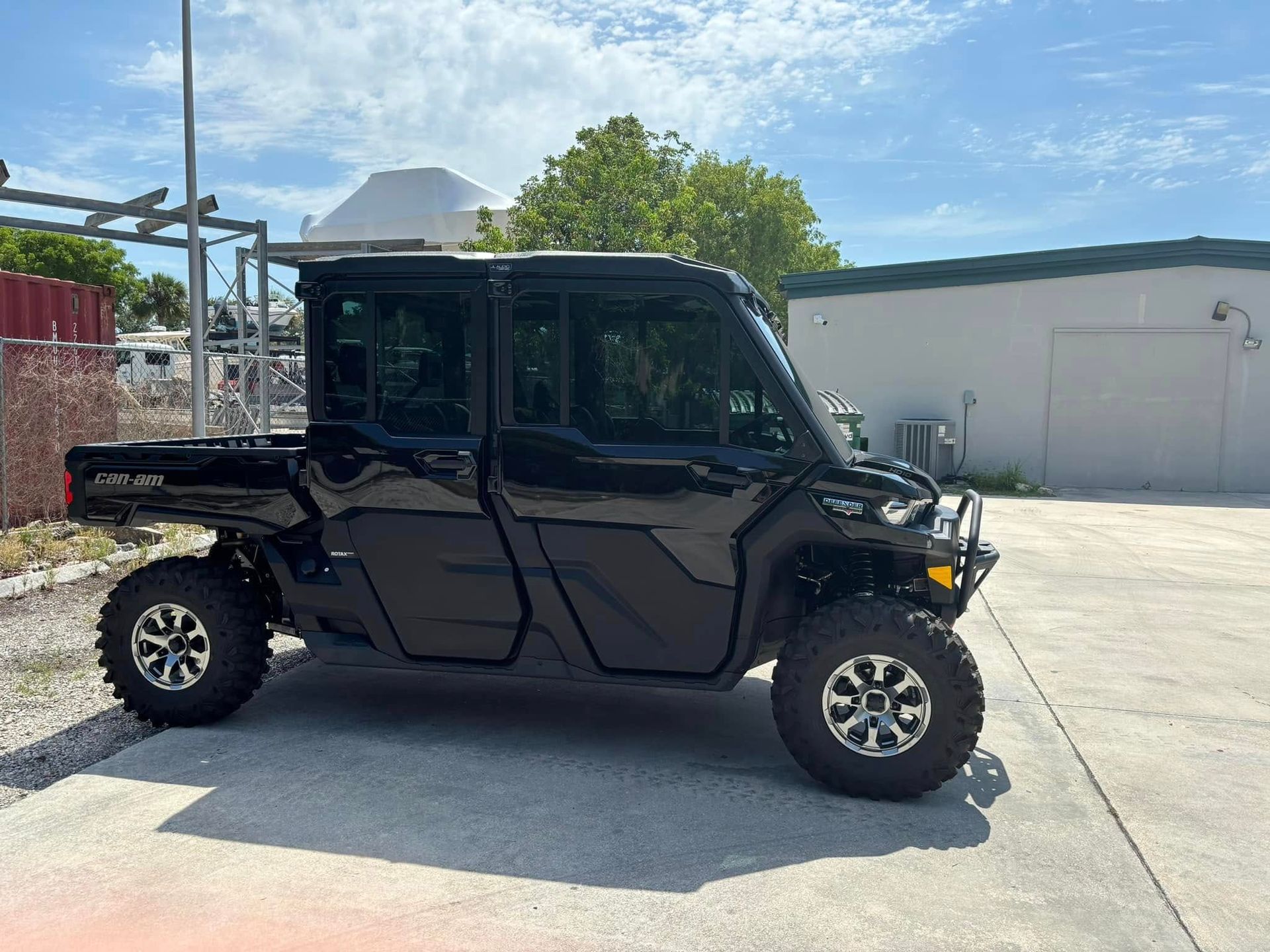 Dark side-by-side utility vehicle with an enclosed cab and rear cargo bed, shown in profile.