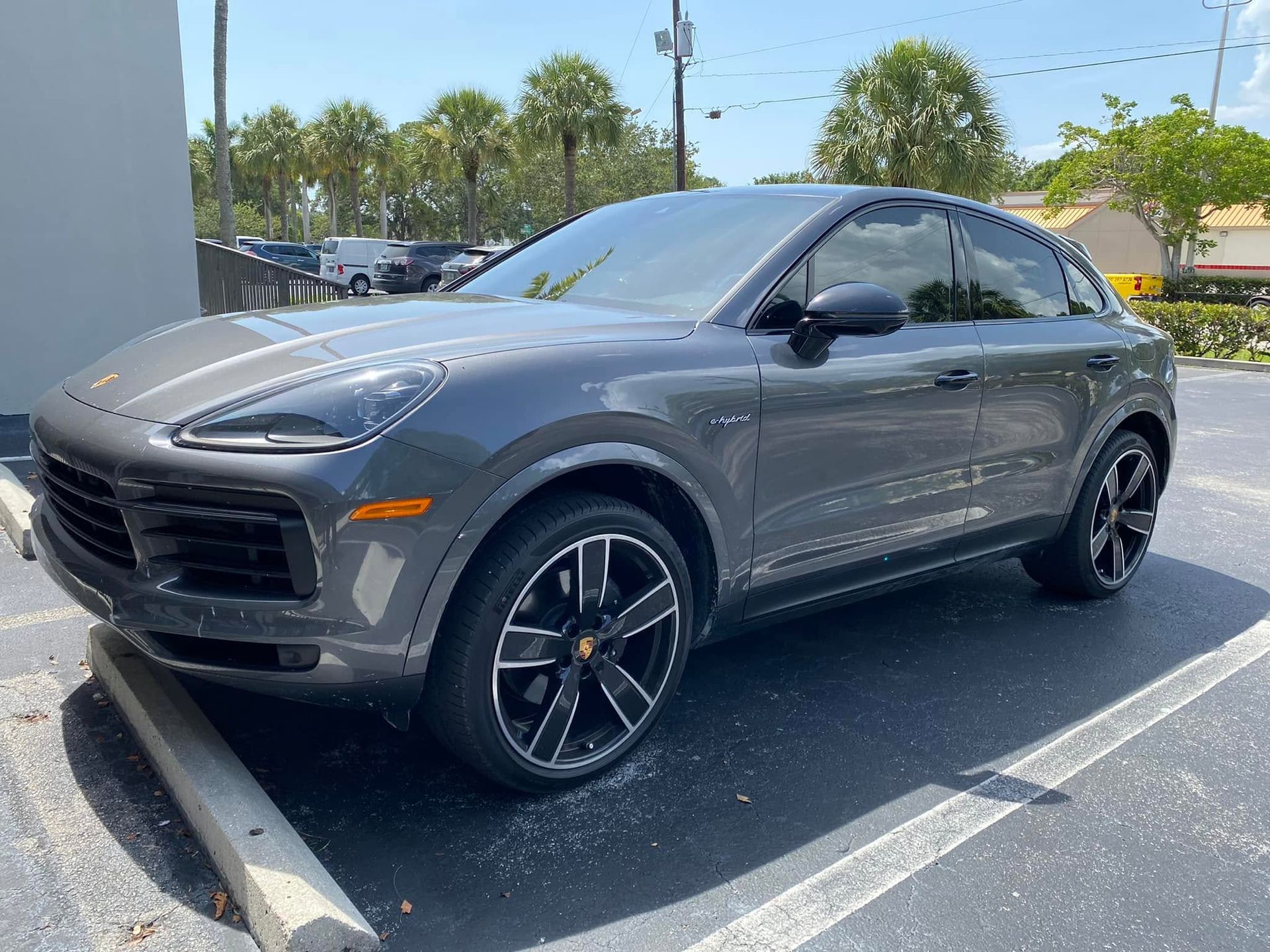 Gray Porsche SUV with dark side windows, viewed from the front and side.