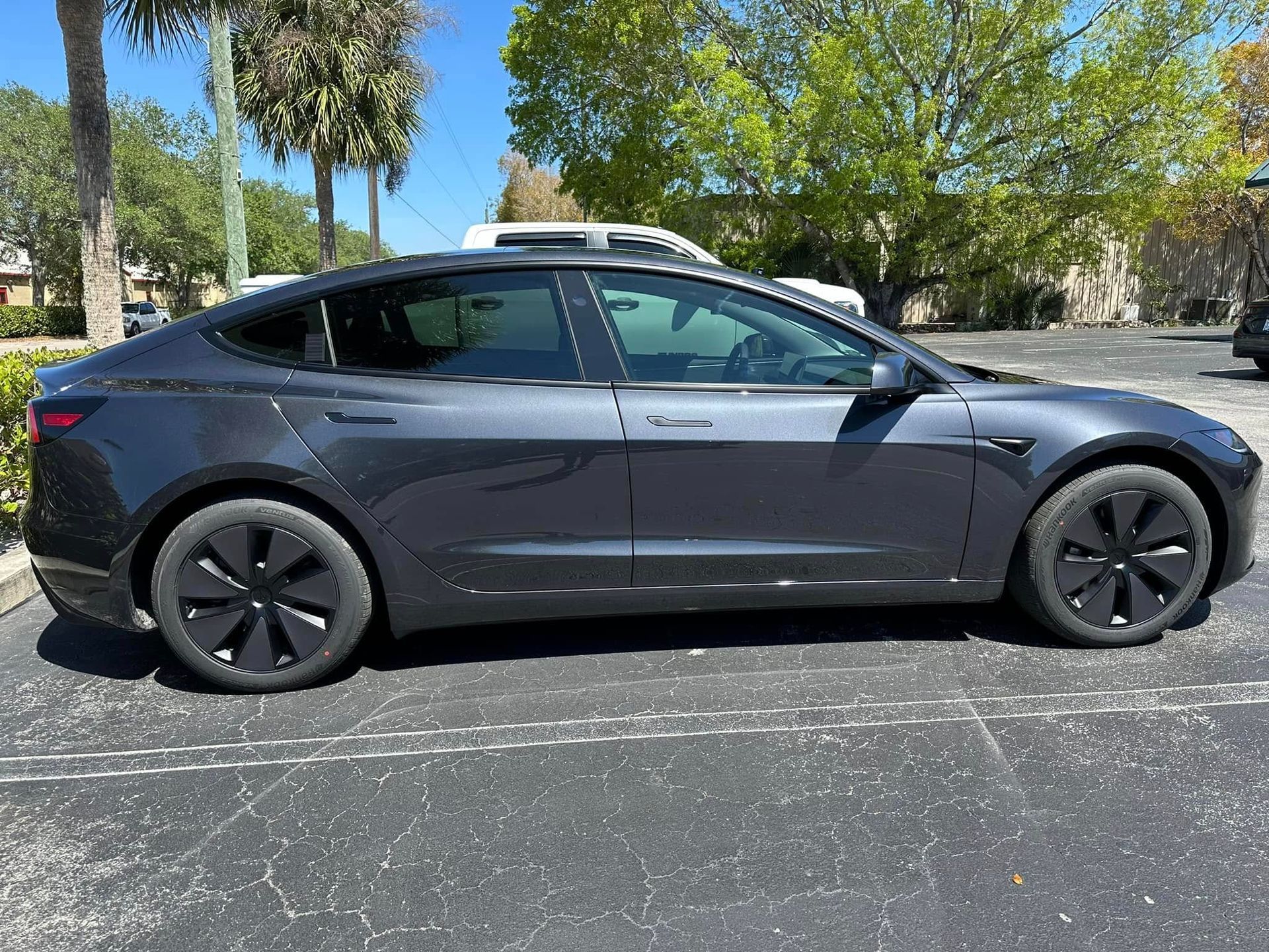 Gray Tesla sedan shown in profile with its side windows visible.