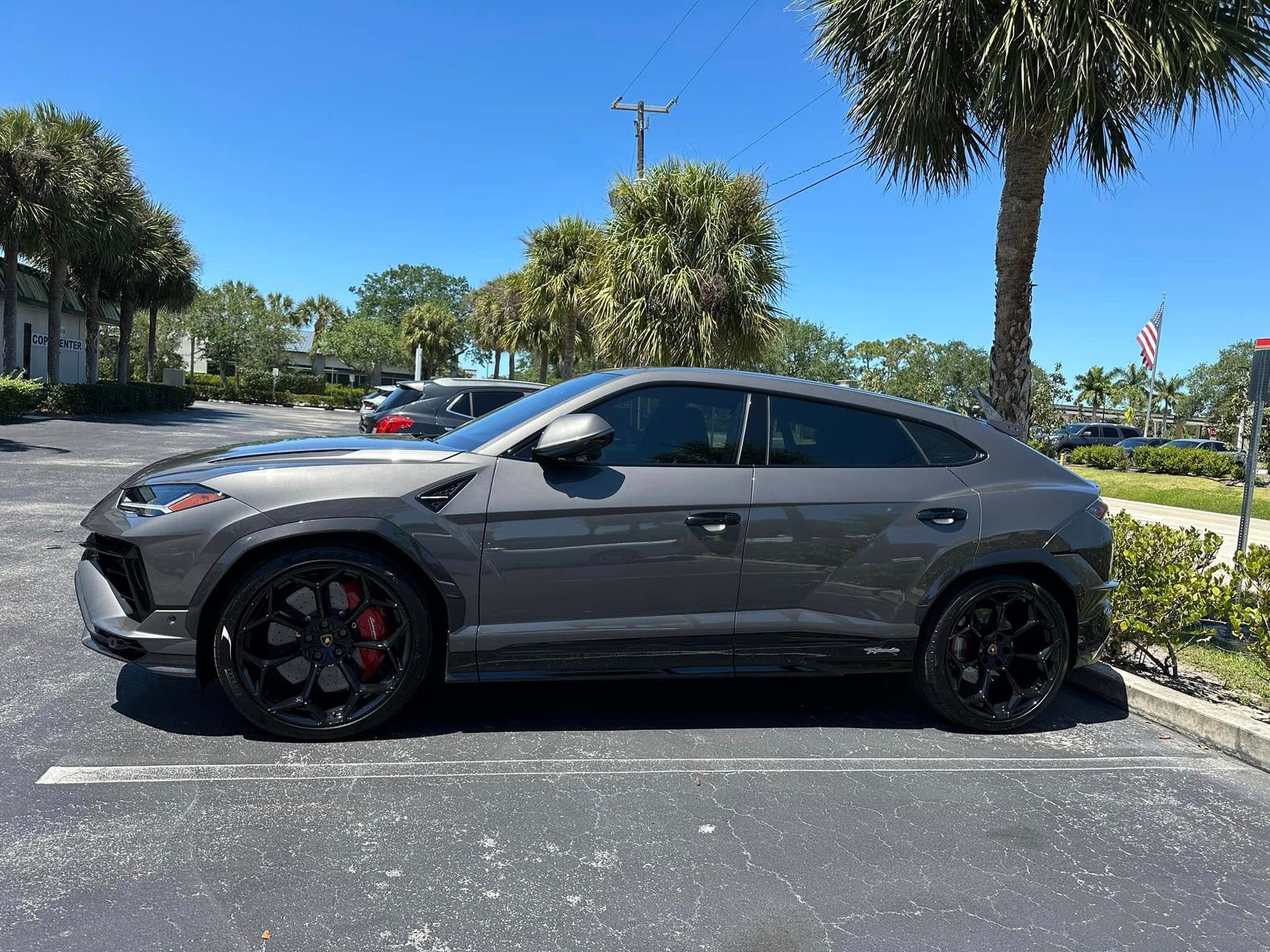 Gray Lamborghini SUV with dark side windows and black wheels, shown in profile.