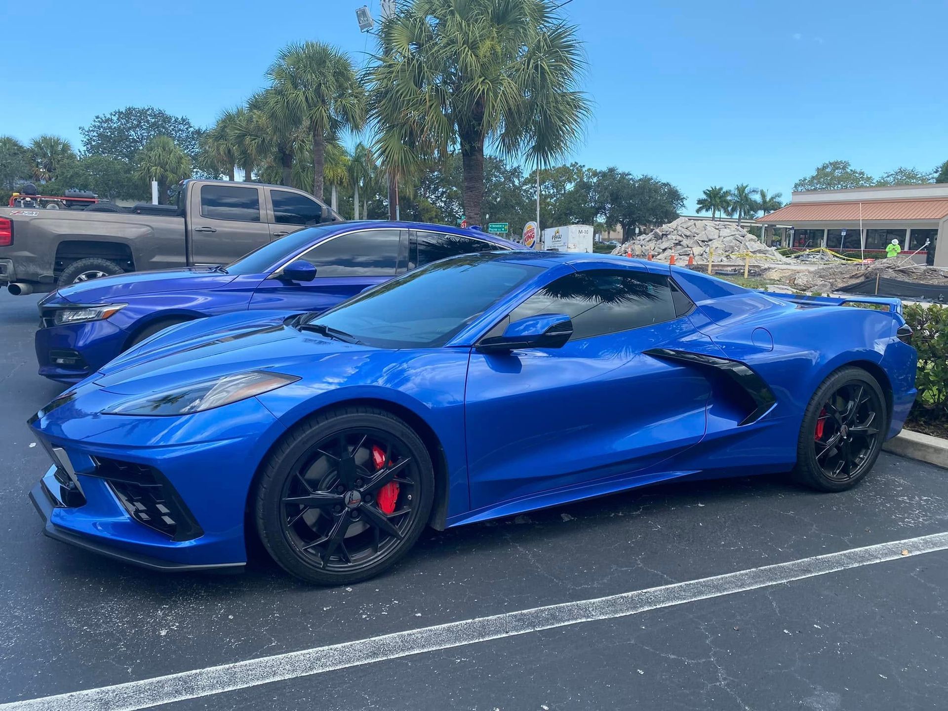 Blue Chevrolet Corvette with dark windows and black wheels, viewed from the front and side.