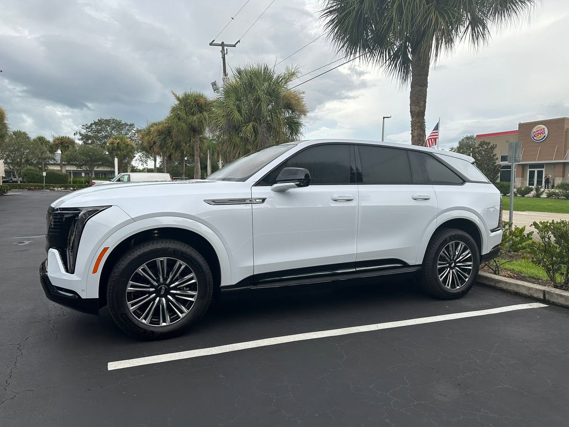 White Cadillac SUV with dark rear windows, viewed from the front and side.