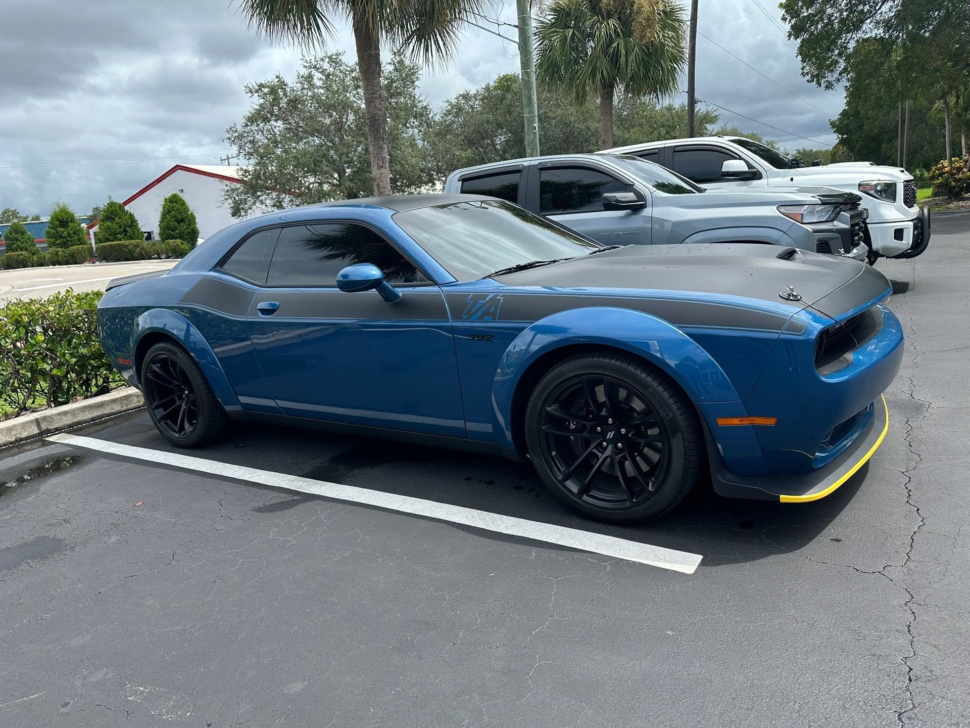 Blue Dodge coupe with a black hood and dark side windows, viewed from the front and side.