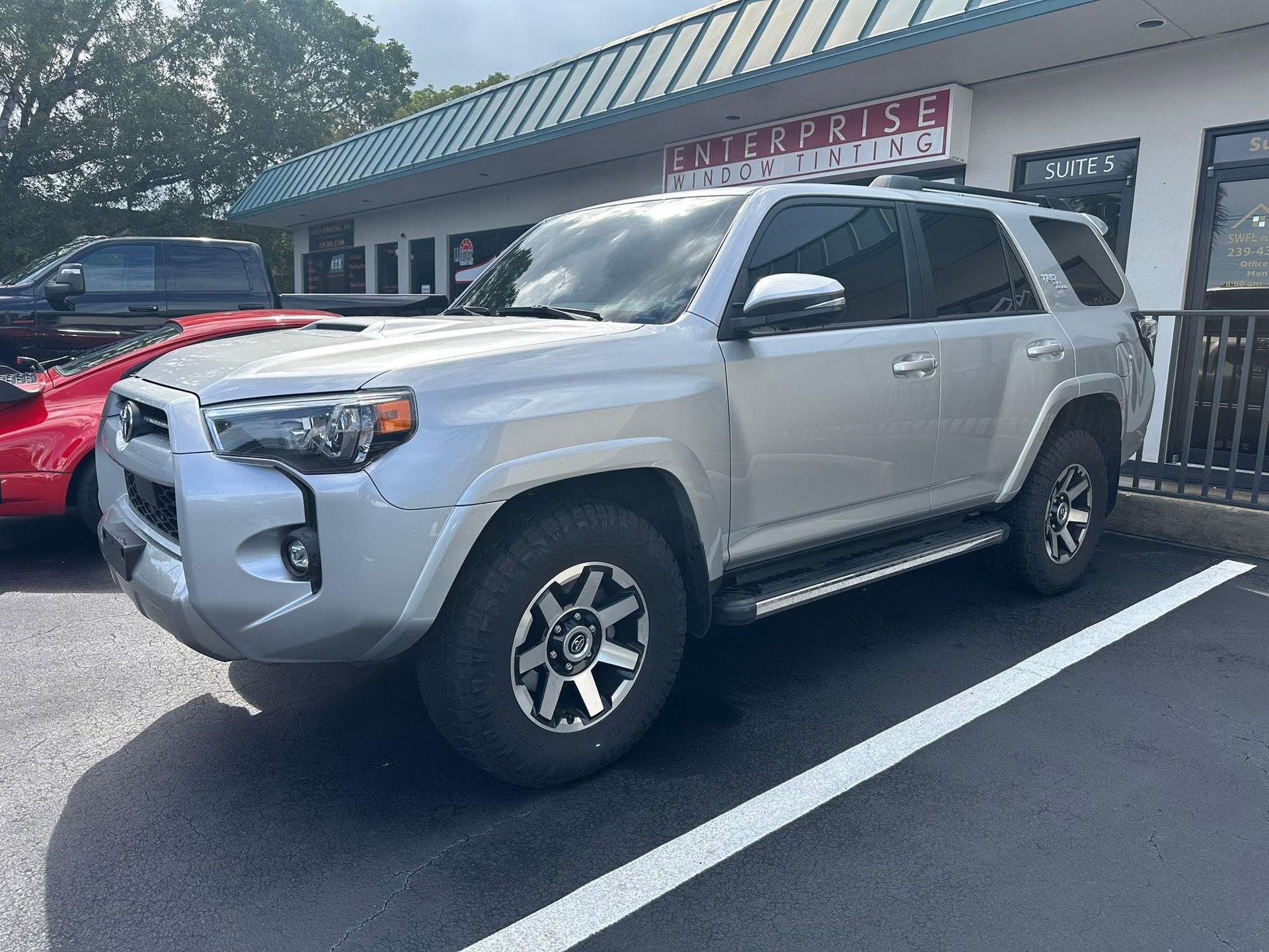 Silver Toyota SUV with dark side windows, viewed from the front and side outside the tint shop.