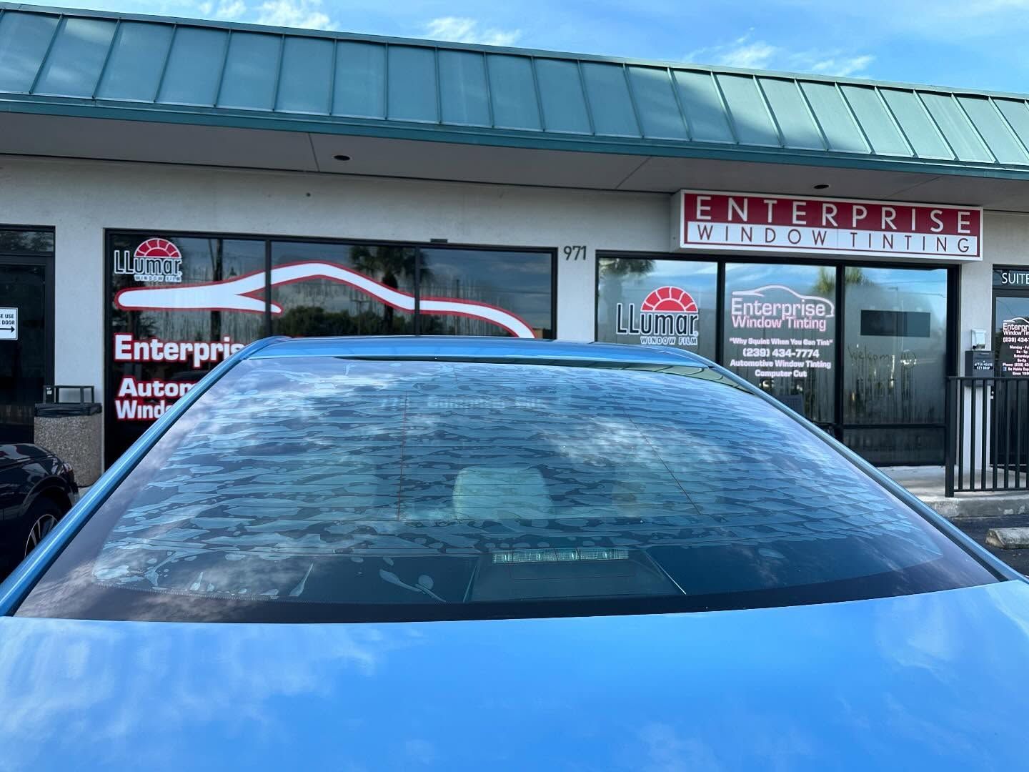 Close-up of a blue car’s rear window outside Enterprise Window Tinting.