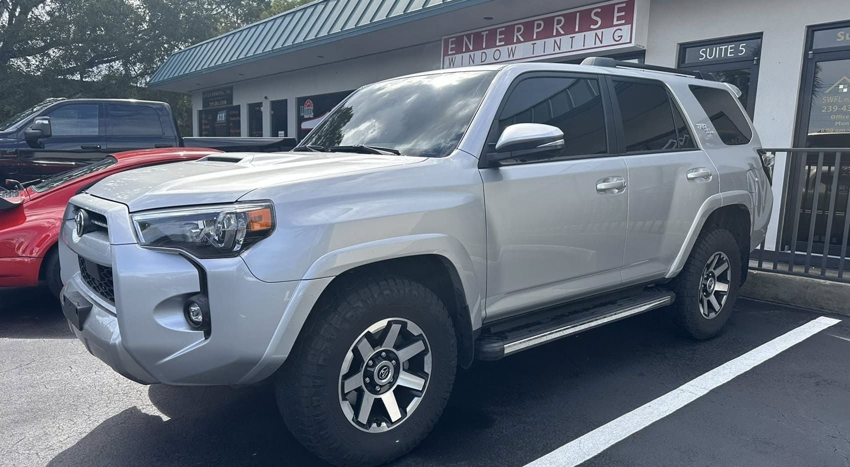 Silver SUV with dark rear windows parked outside a window-tinting storefront.
