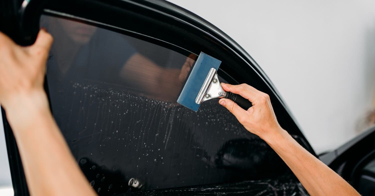 Installer using a squeegee on car window film