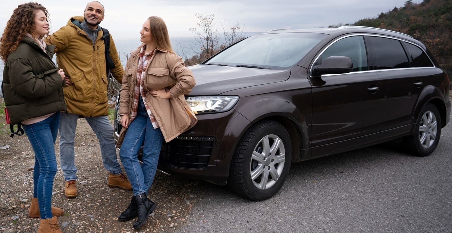 Three adults standing beside a dark SUV on a roadside.