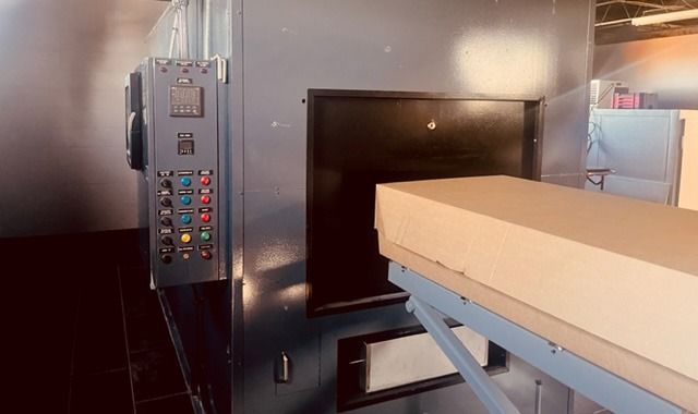 Industrial machine with control panel and a conveyor belt entering a dark chamber