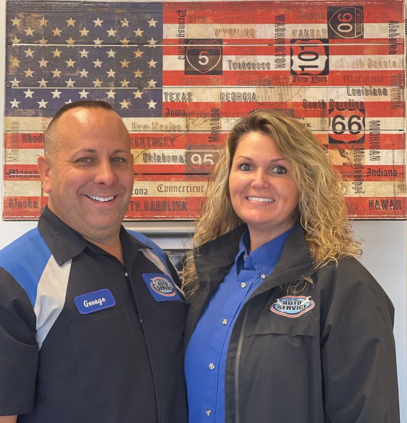 A man and a woman are posing in front of an american flag
