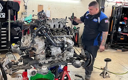 A man is working on a car engine in a garage.