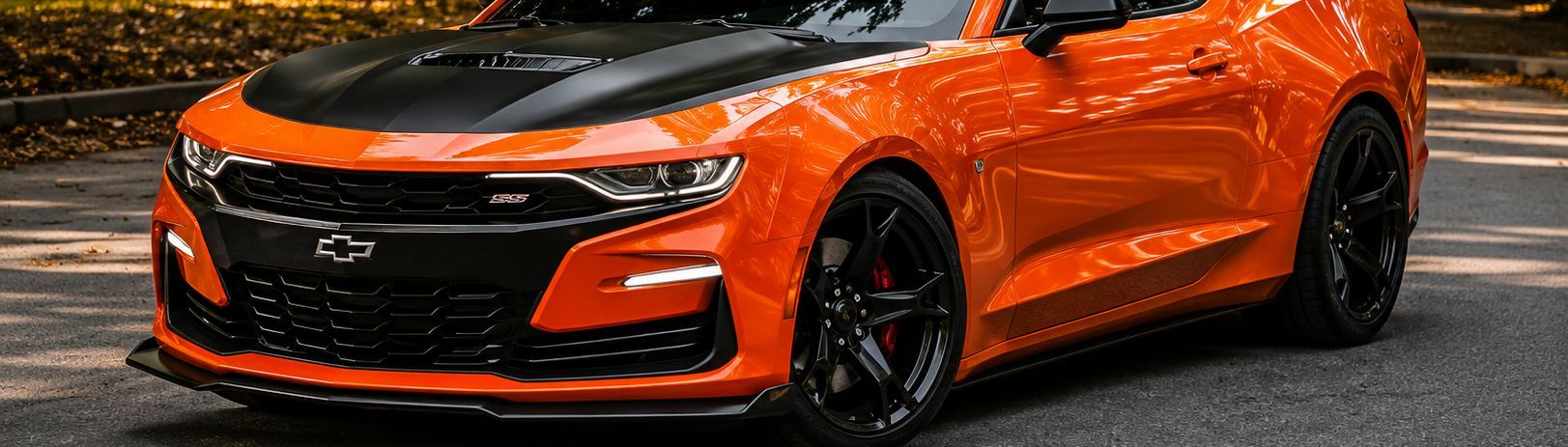 Orange sports car parked on a road, front-left view with black accents and wheels.