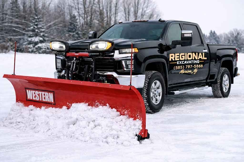 Black pickup truck with a red snowplow clearing snow. Snow-covered ground, winter setting.