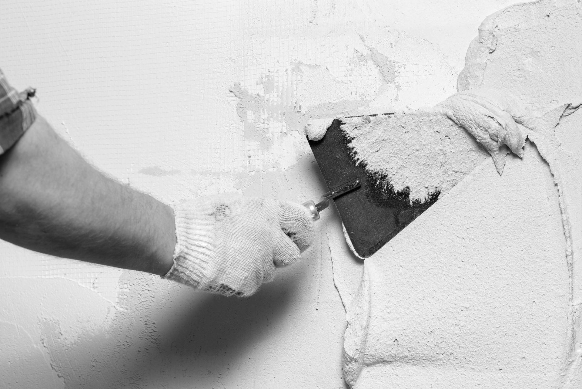 Une personne enduit un mur avec une truelle.