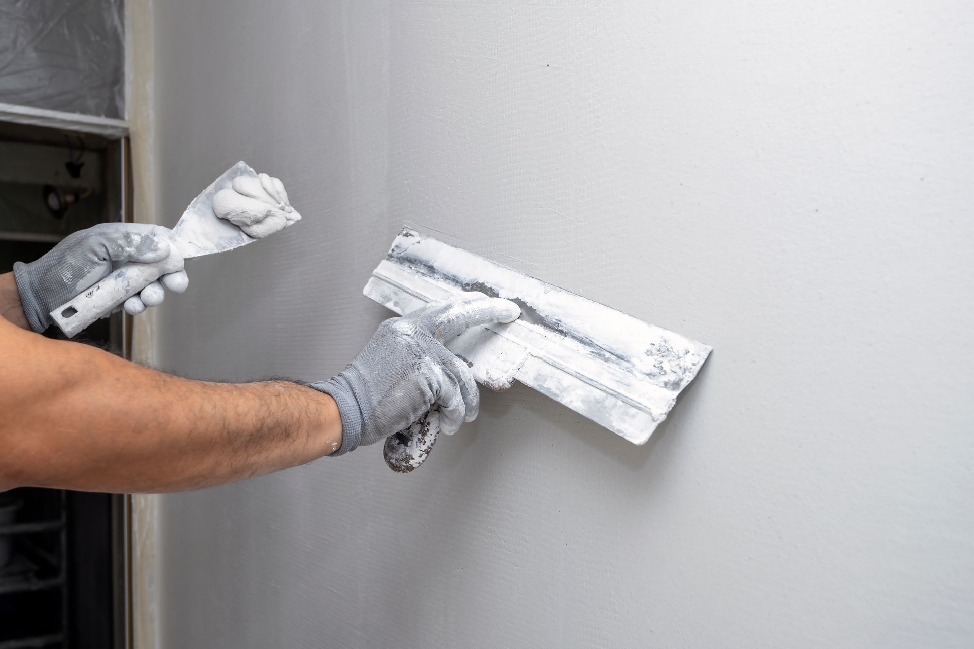 Un homme enduit un mur avec une spatule.