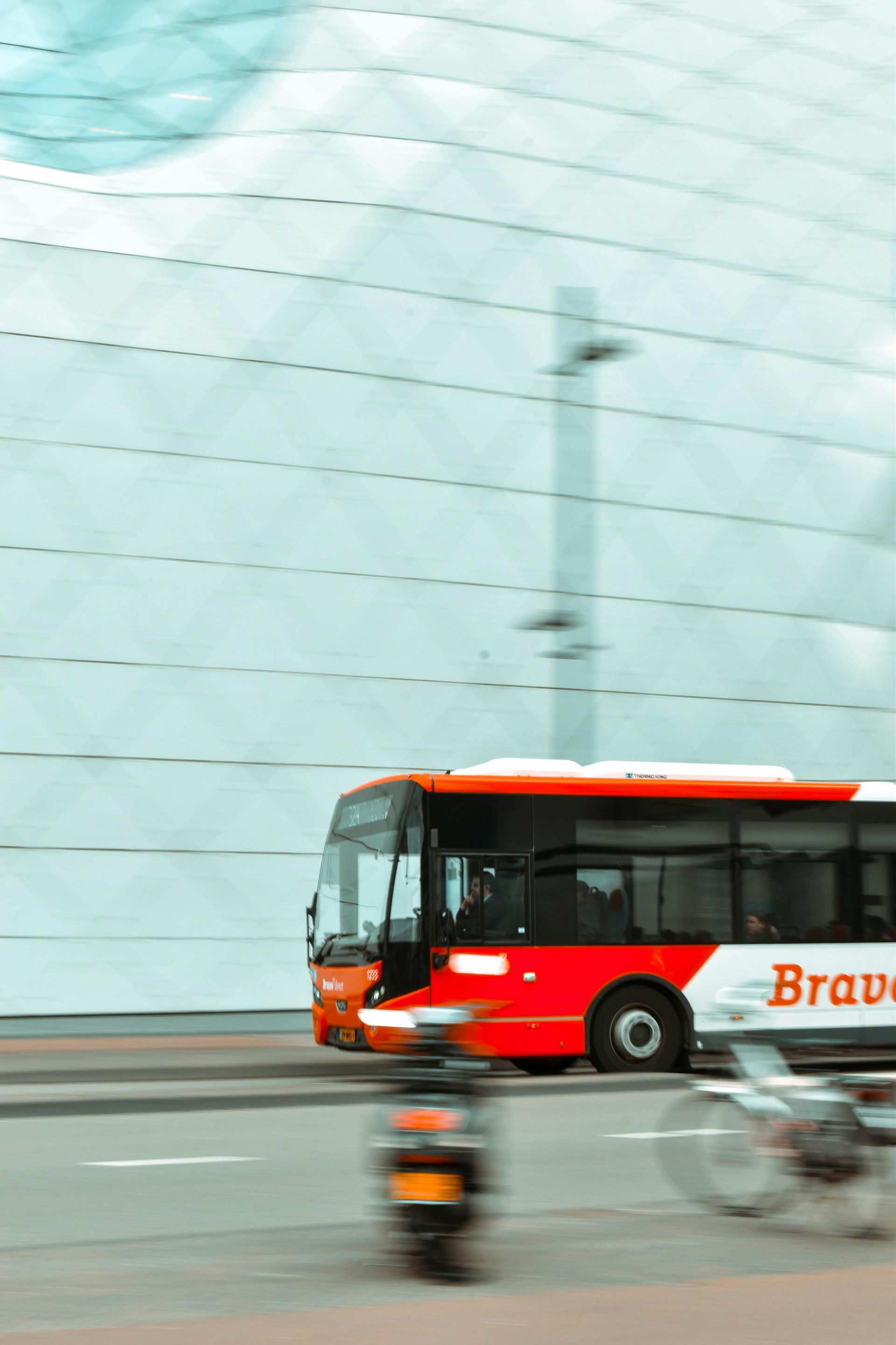 A red and white bus is driving down a street.