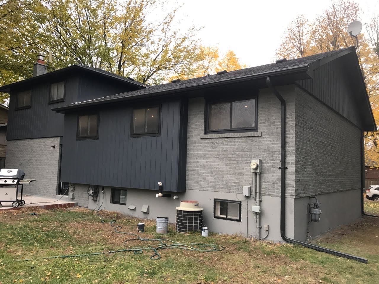 the back of a house with a grill in the backyard