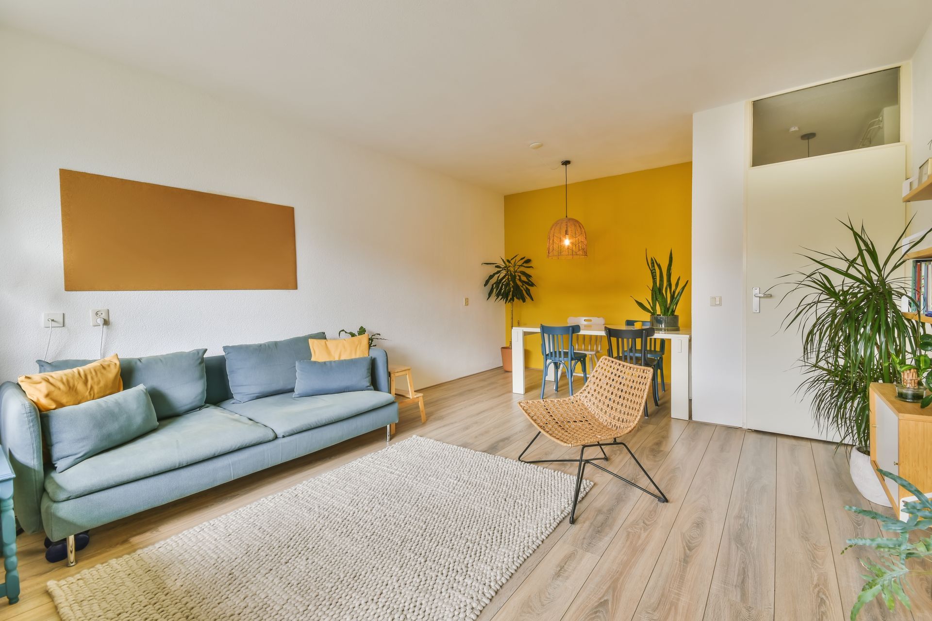 a living room with a blue couch , chair , rug and yellow walls .