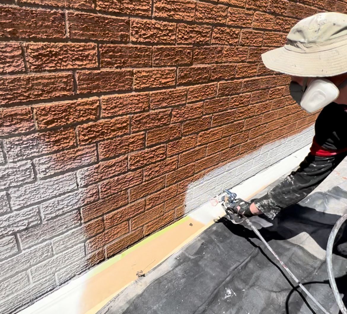 a man wearing a hard hat is holding a brick and smiling .