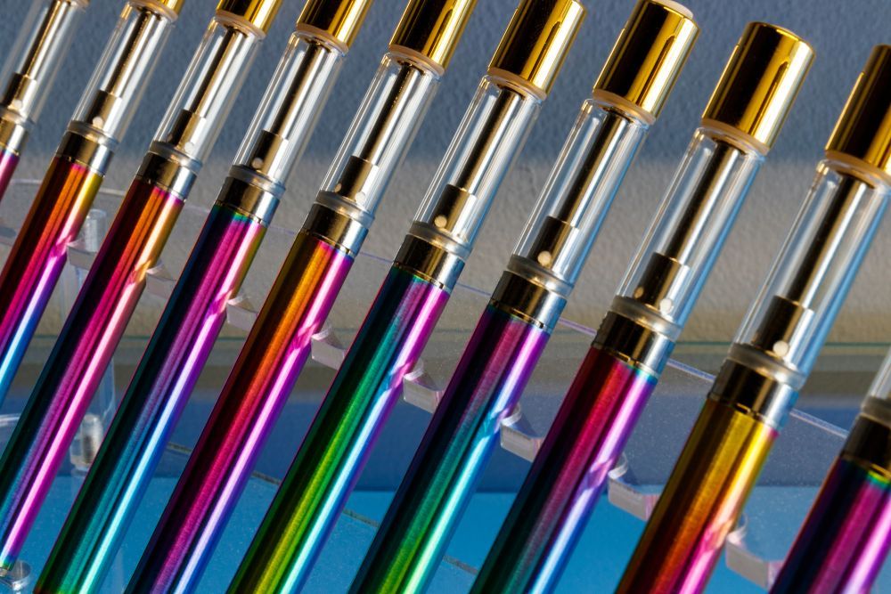 Colorful rows of paintbrushes with gold ferrules, laid diagonally on a reflective surface.