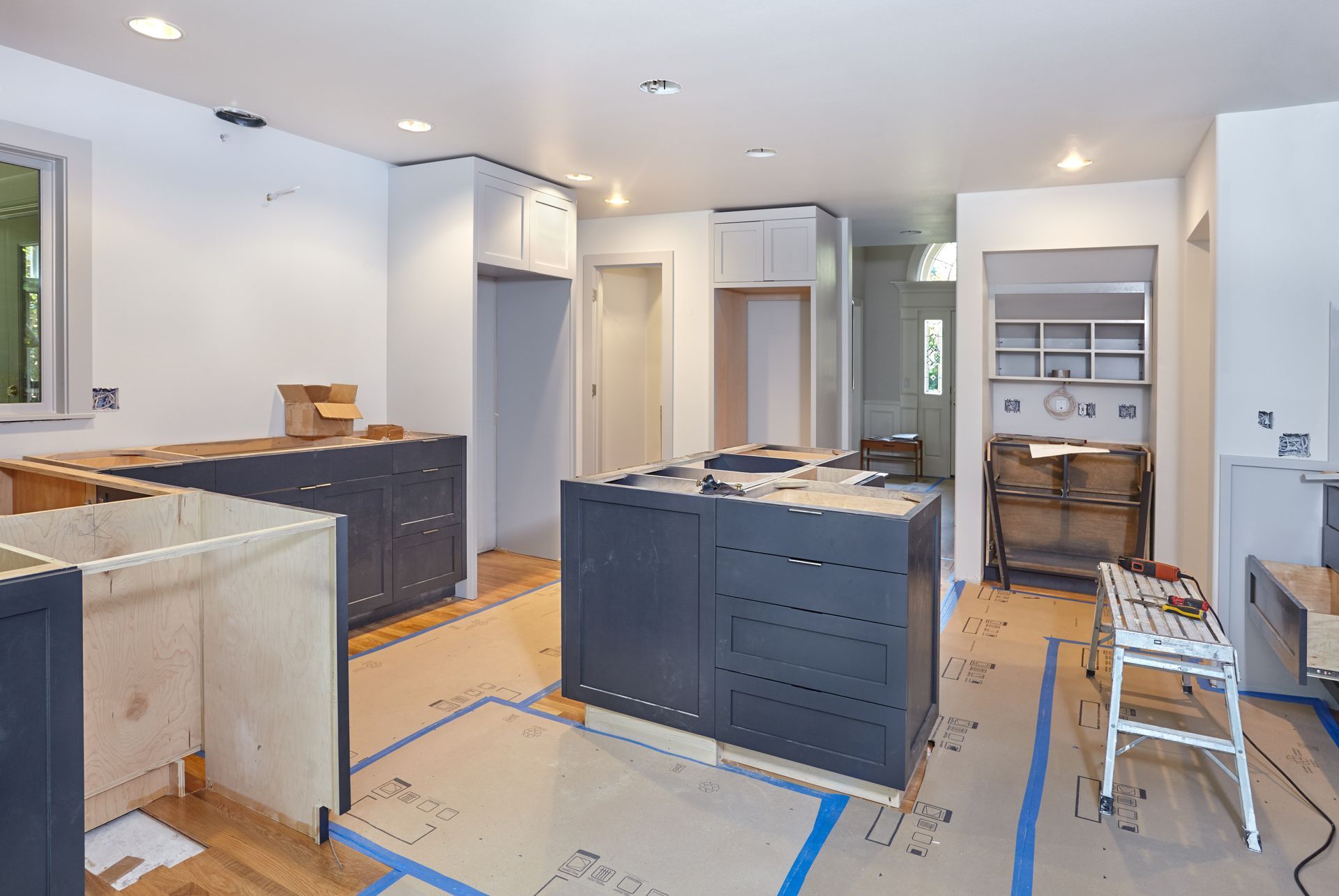 A kitchen under construction, featuring cabinets and countertops being installed.
