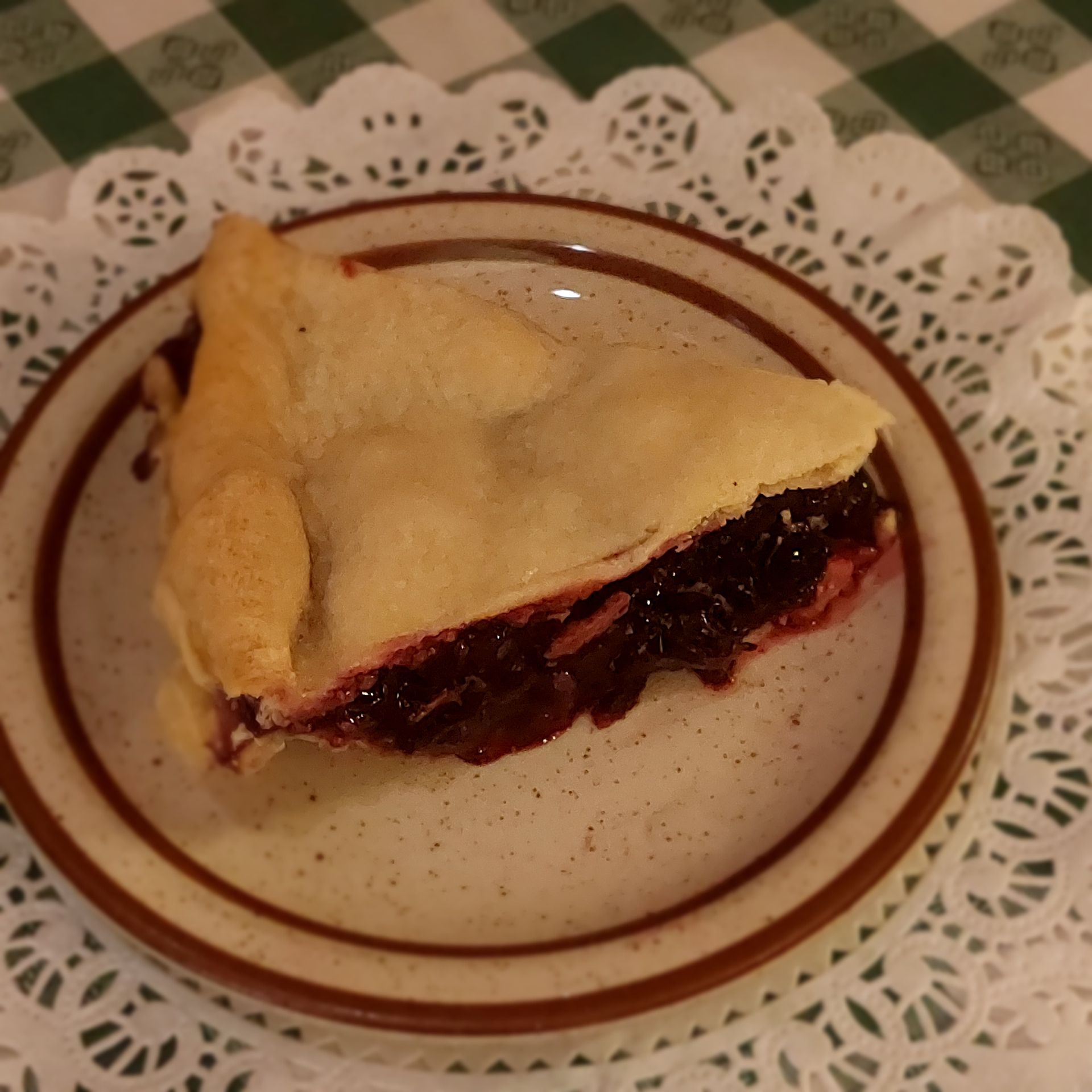 Slice of berry pie on a white plate with a lace doily border